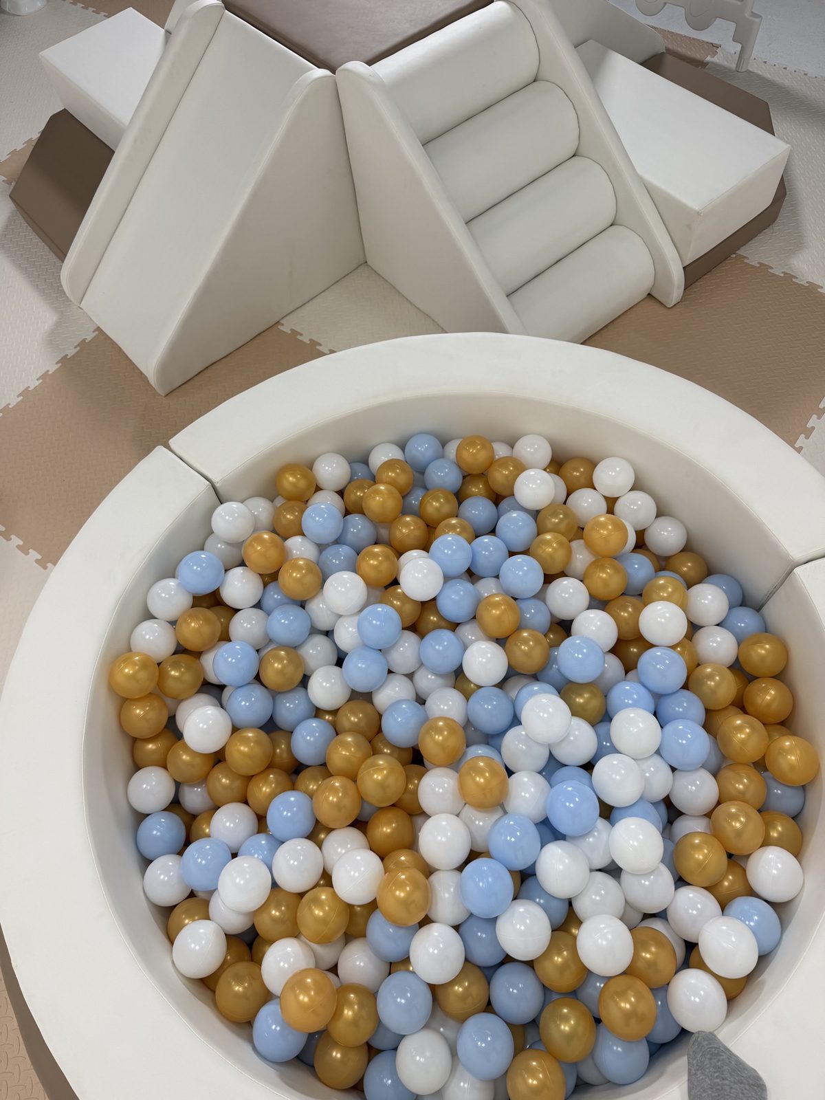 Close view of a ball pit filled with blue, white and gold balls