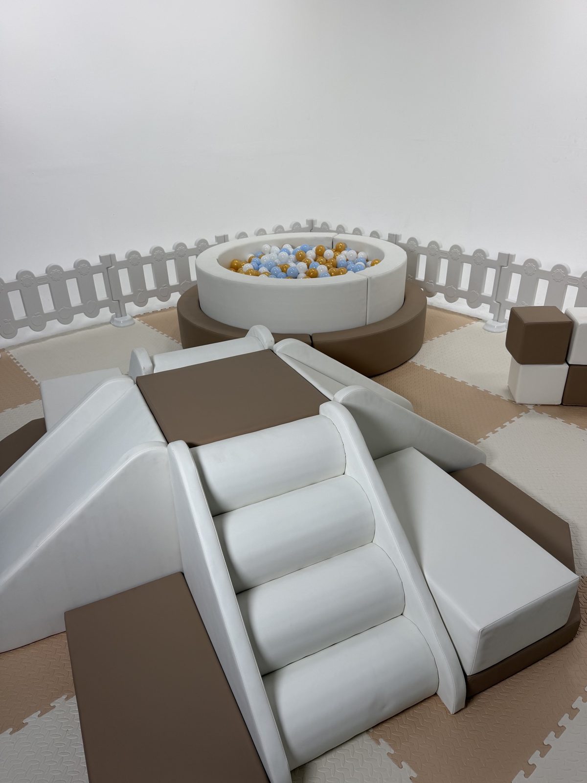 Full neutral soft-play setup with ball pit, slide, climbers and white fence