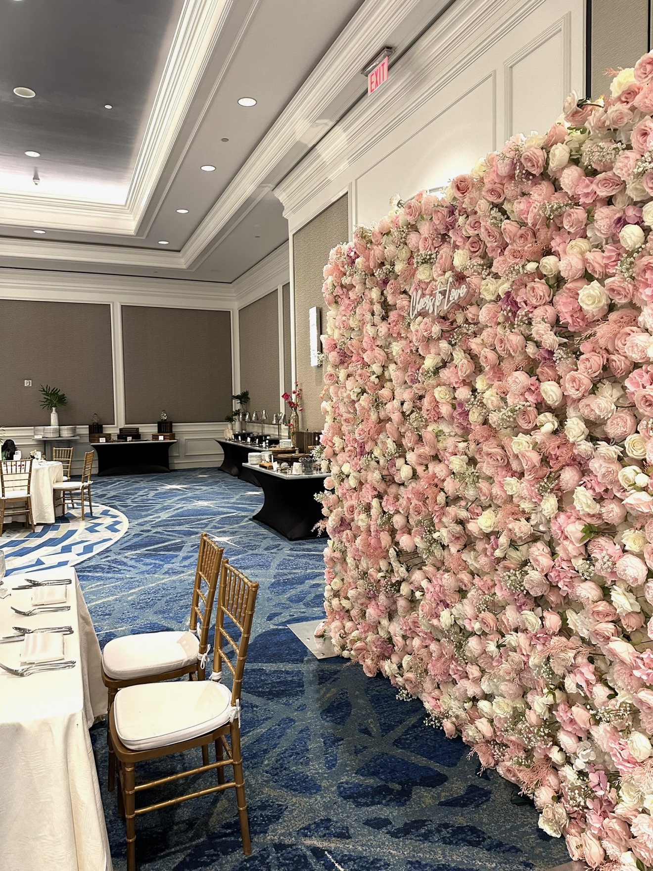 Cheers to Love flower wall in a ballroom with gold Chiavari chairs and set tables